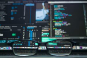 Eyeglasses reflecting computer code on a monitor, ideal for technology and programming themes.