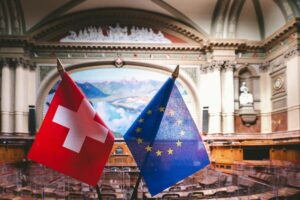 Swiss and EU flags inside the Swiss Parliament building in Bern, showcasing political unity.