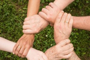 Close-up of diverse hands forming a connection, symbolizing teamwork and unity outdoors.